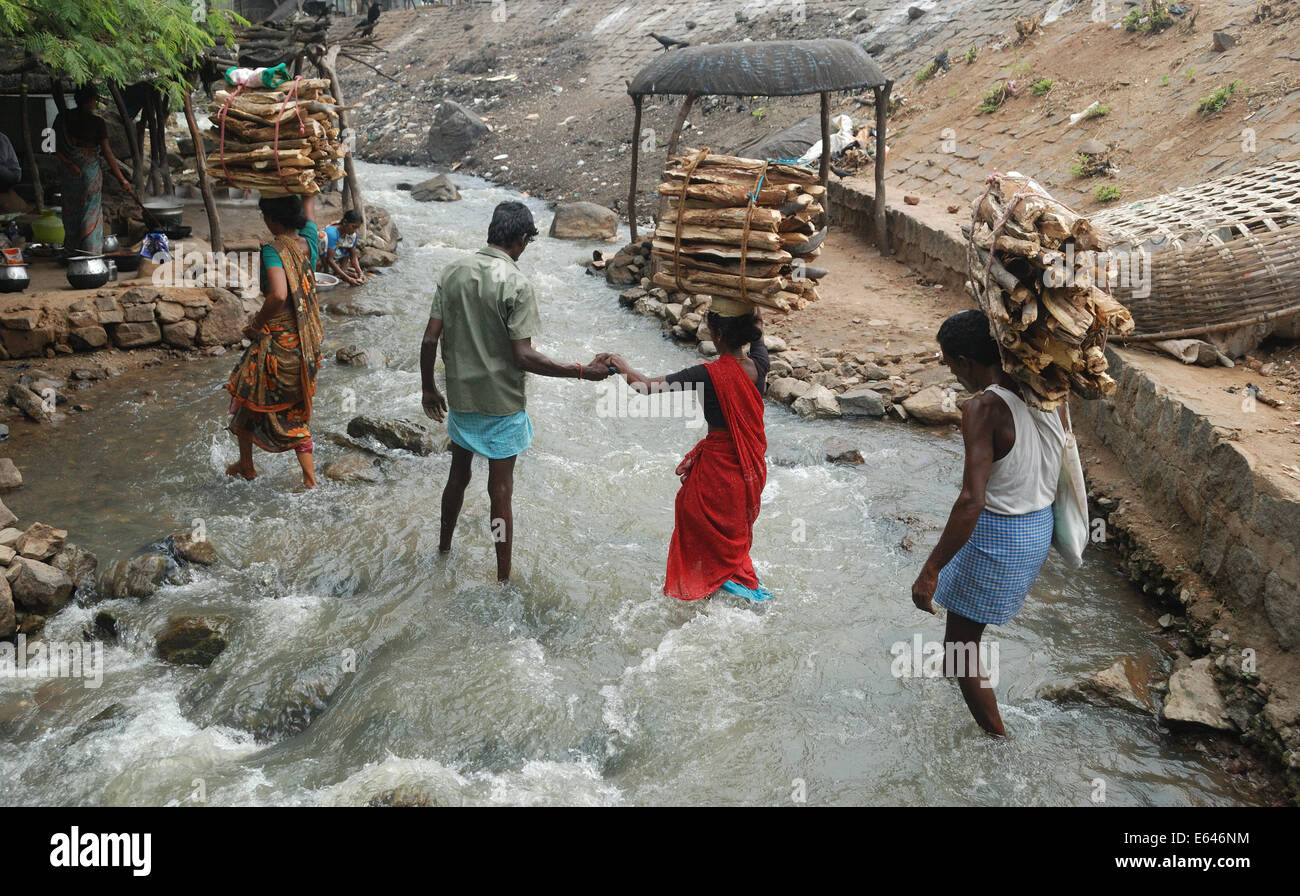 Un uomo aiutando ad attraversare il torrente,una scena di un villaggio indiano. Foto Stock