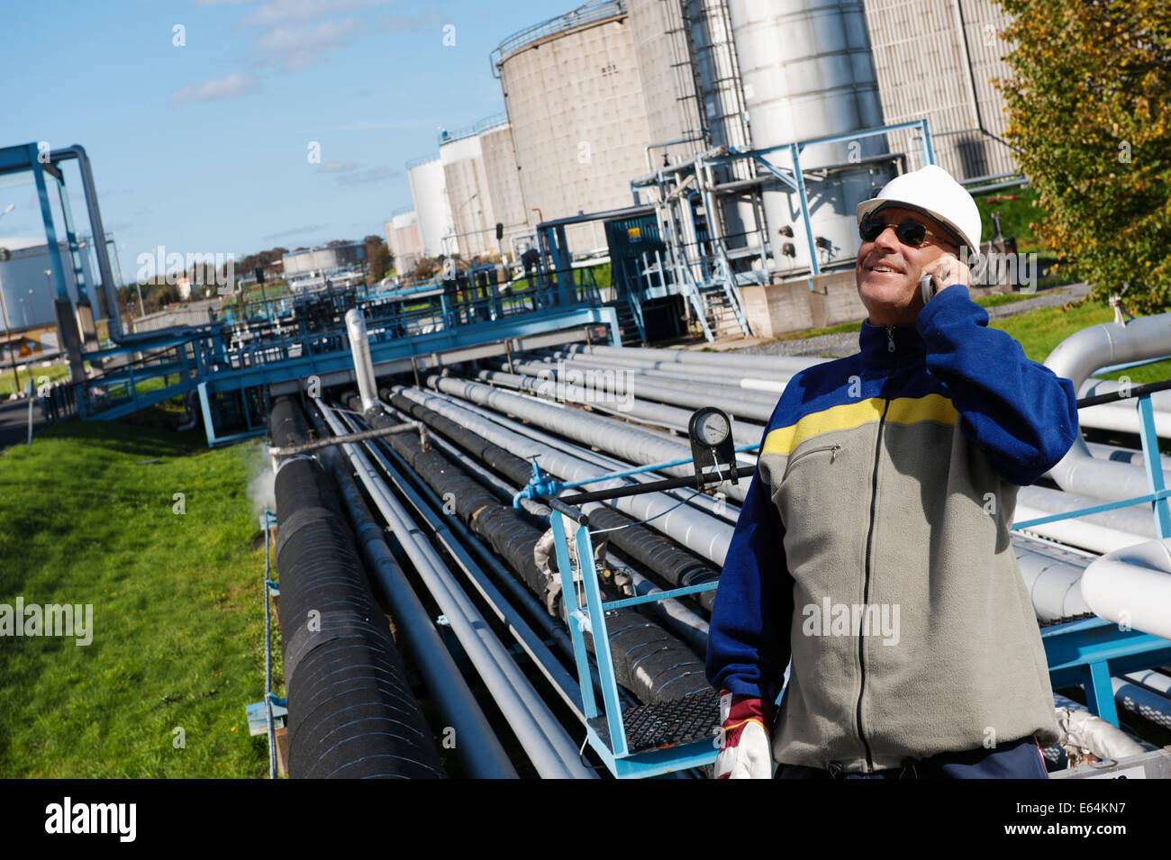 Ingegnere in hard-hat con tubazioni all'interno della raffineria di petrolio Foto Stock