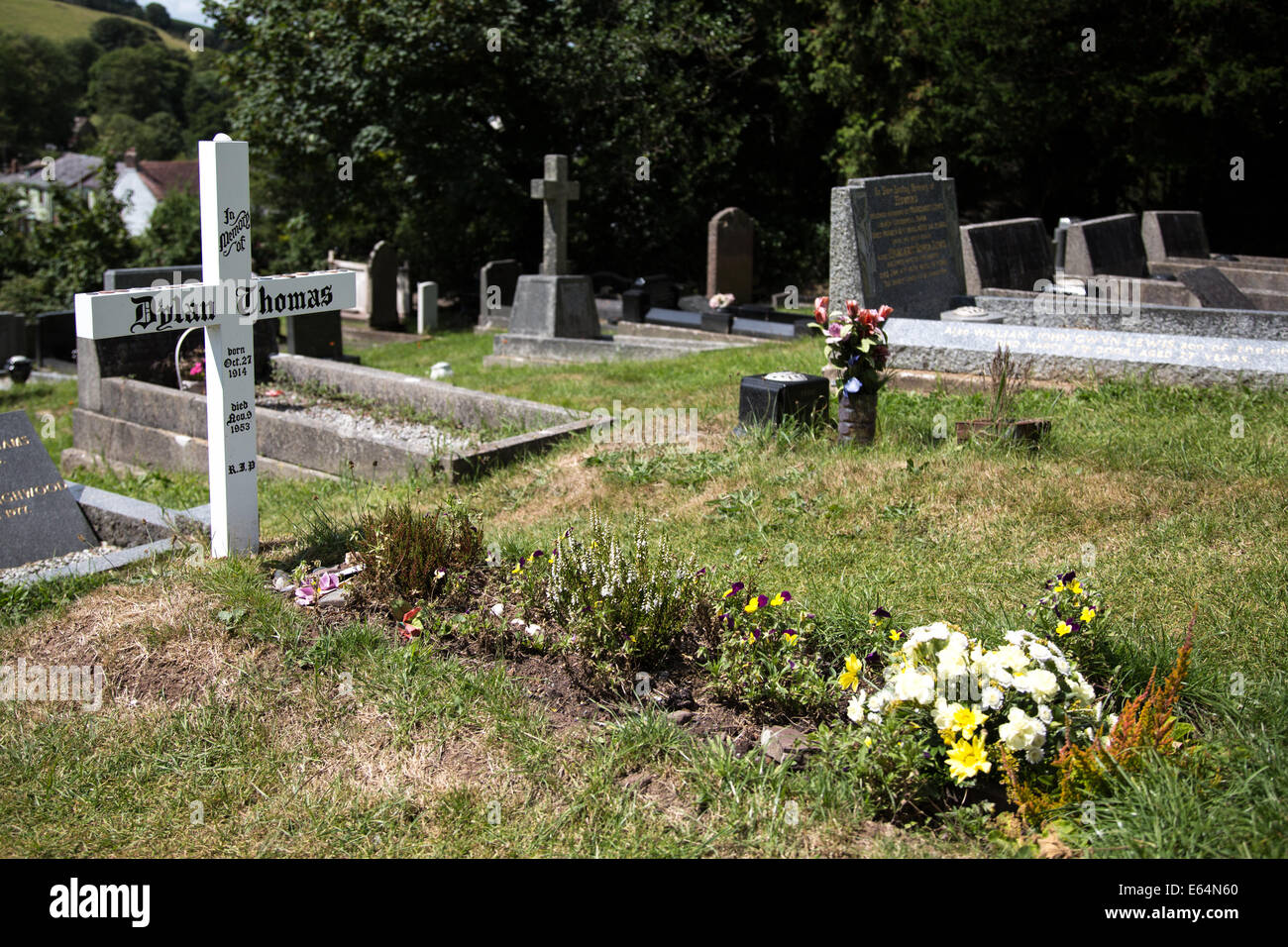 Il nome di Dylan Thomas inscritto in una croce bianca che segna la sua tomba a Laugharne, West Wales Foto Stock