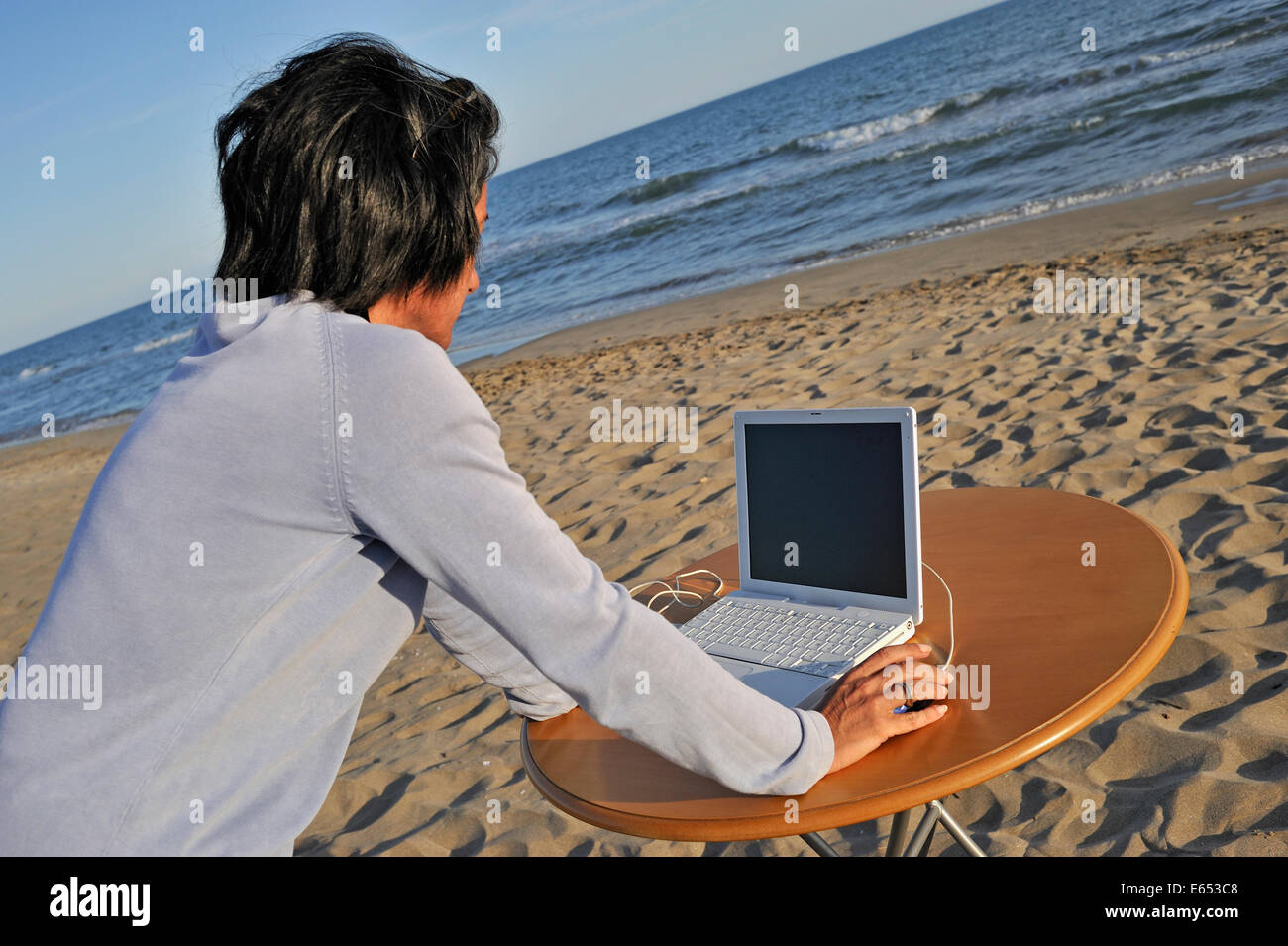 Metà donna adulta usando un computer portatile sulla spiaggia - Vacanze di lavoro concept Foto Stock
