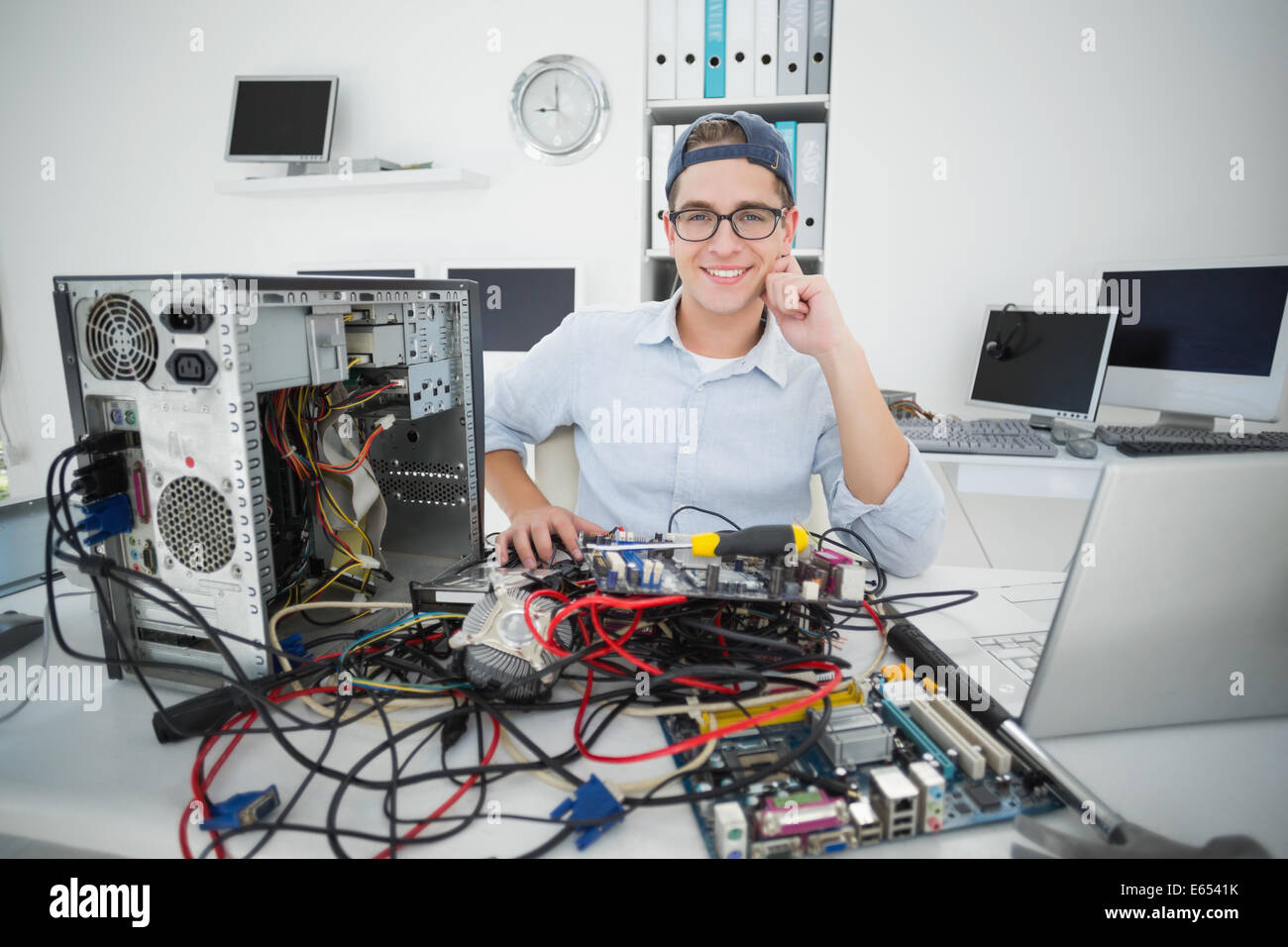 Sorridente tecnico che lavora su computer rotto Foto Stock