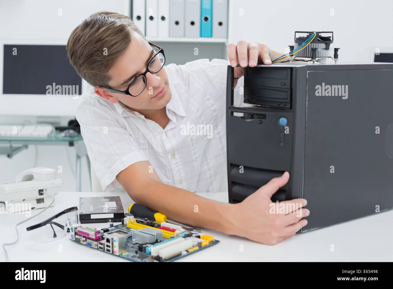 Giovane tecnico che lavora su computer rotto Foto Stock