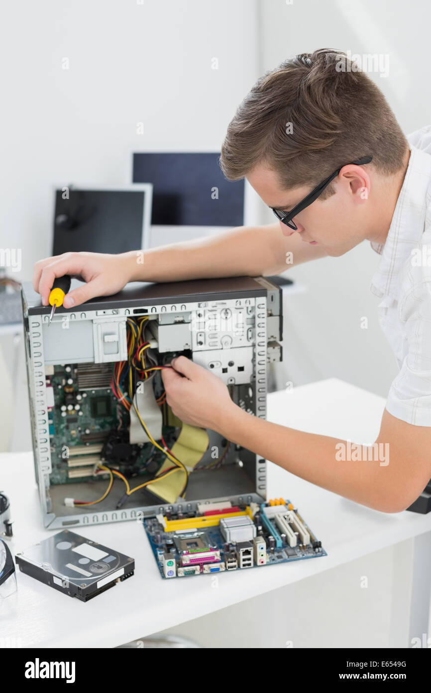 Giovane tecnico che lavora su computer rotto Foto Stock