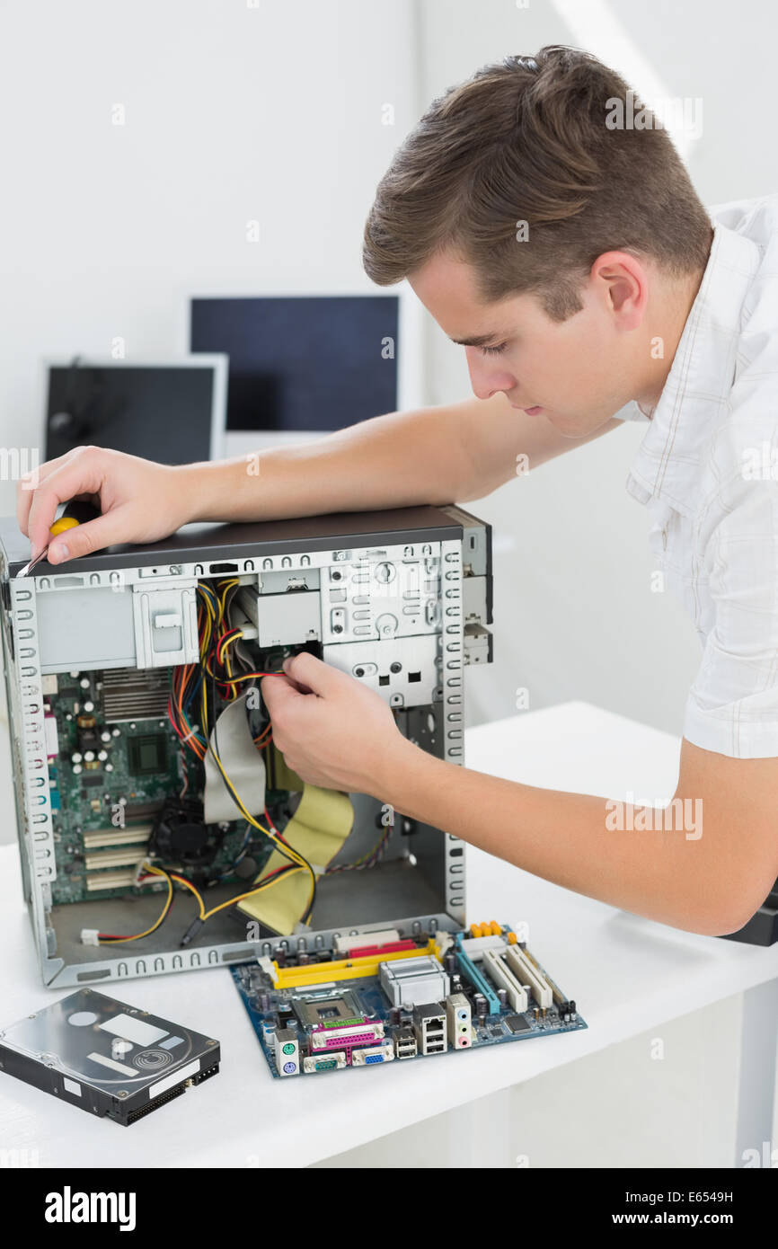Giovane tecnico che lavora su computer rotto Foto Stock