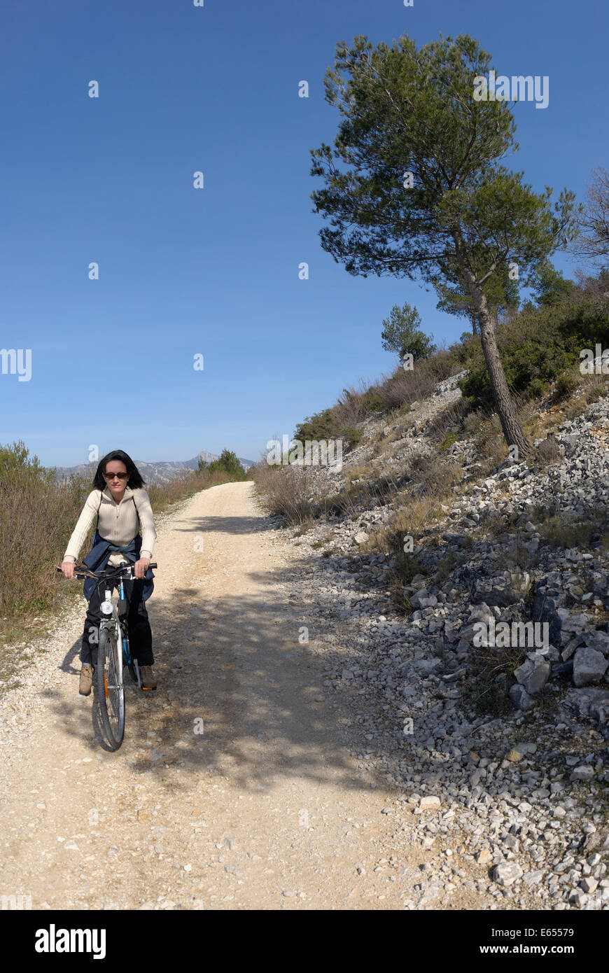Donna ciclista in sella a una moto su una pista sterrata, Provence, Francia Foto Stock