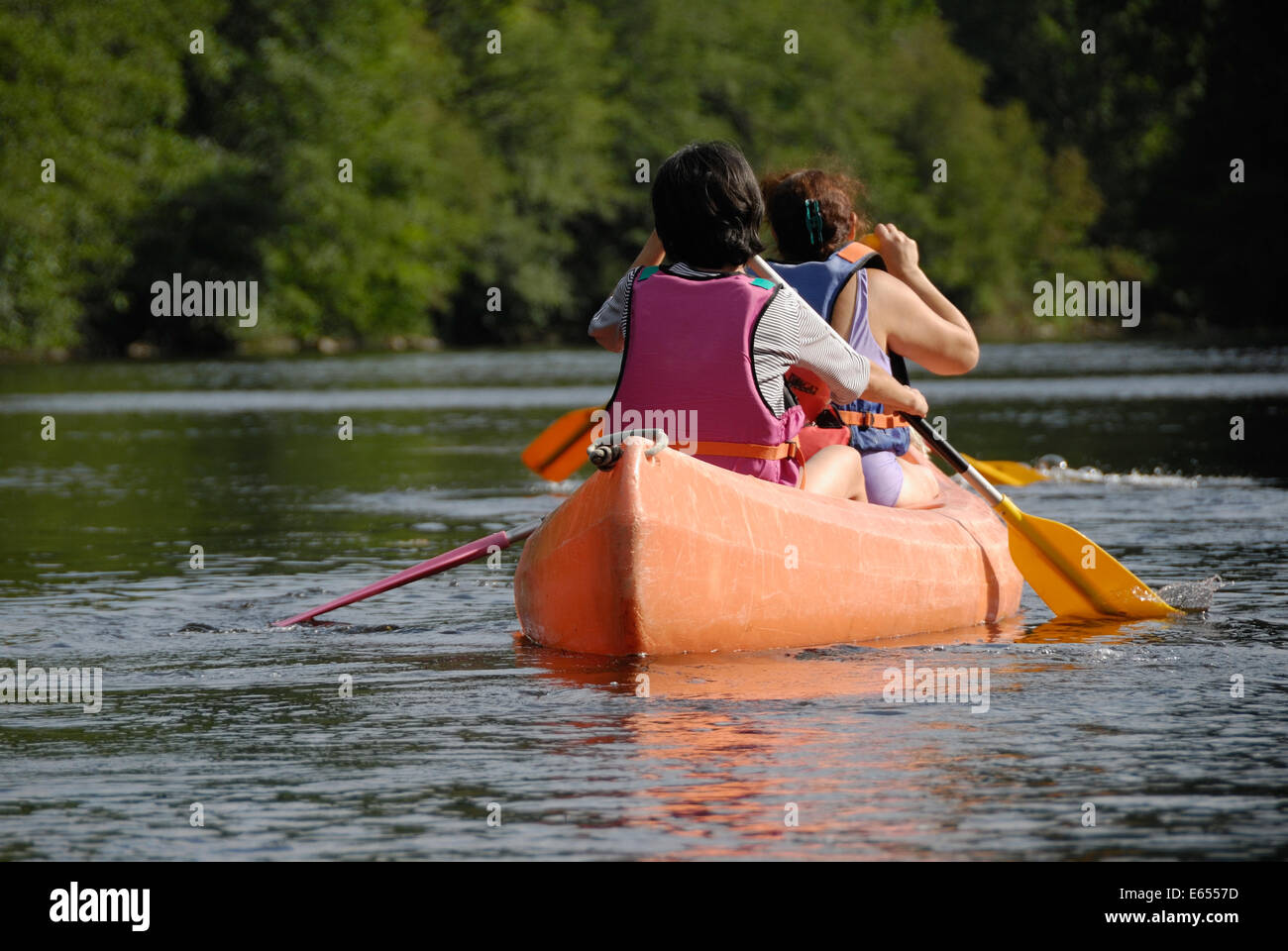 Due donne canottaggio una canoa / kayak sulle rive di un fiume Foto Stock