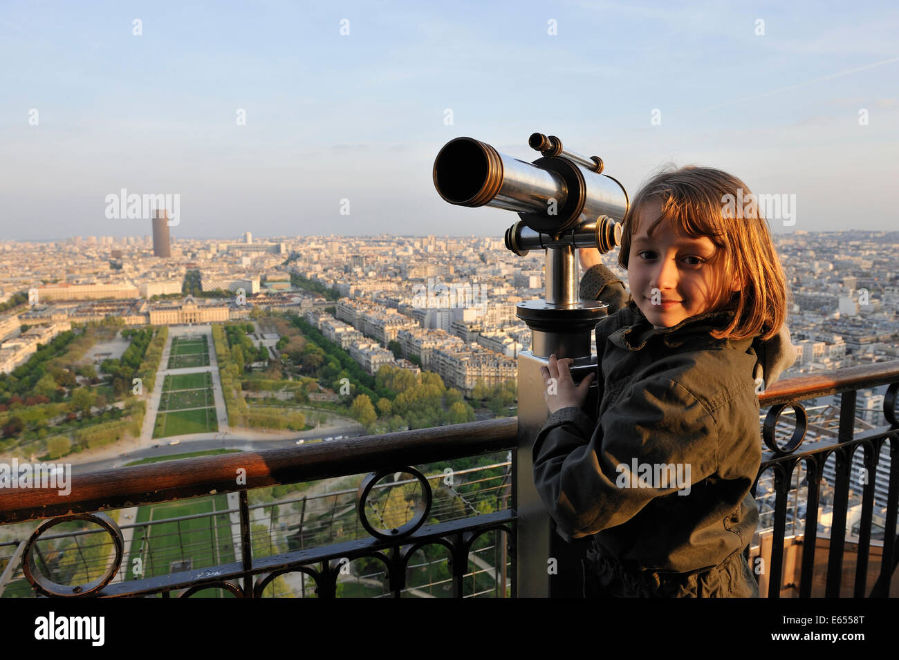 Ragazza giovane alla sommità della torre Eiffel, Parigi, Francia, Europa - con la Torre di Montparnasse e Parc du Champ de Mars in background Foto Stock