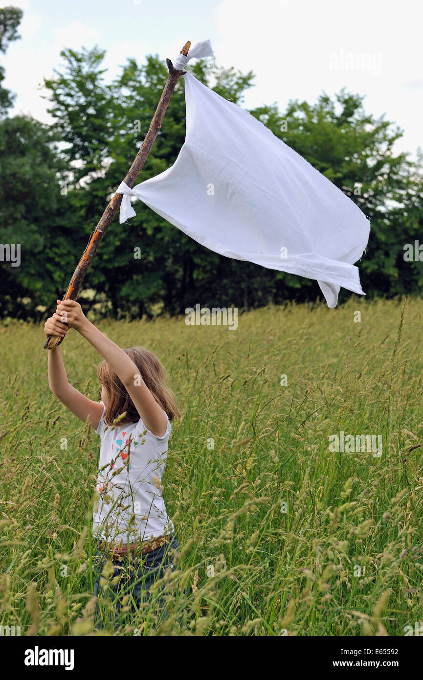 Ragazza giovane (di età compresa tra i 8) sollevando la bandiera bianca e arrendersi Foto Stock
