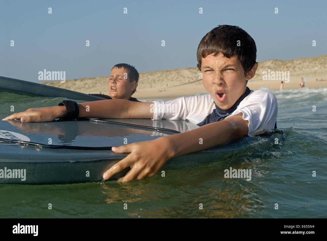 Due giovani ragazzi / giochi per bambini all aperto con tavole da surf in attesa di una grande onda in vacanza, le porge, Gironde, Francia, Europa Foto Stock