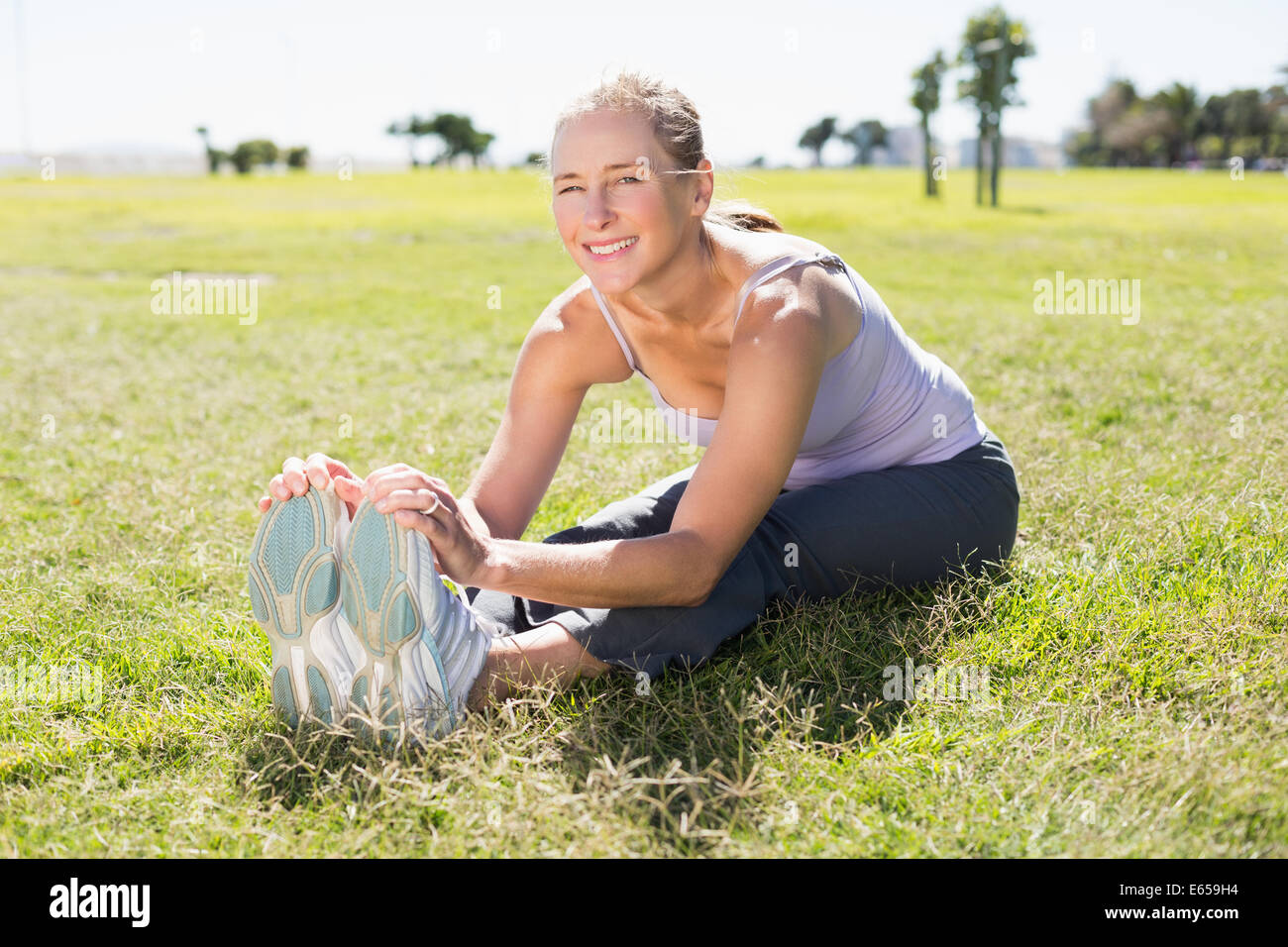Montare donna matura in fase di riscaldamento sull'erba Foto Stock