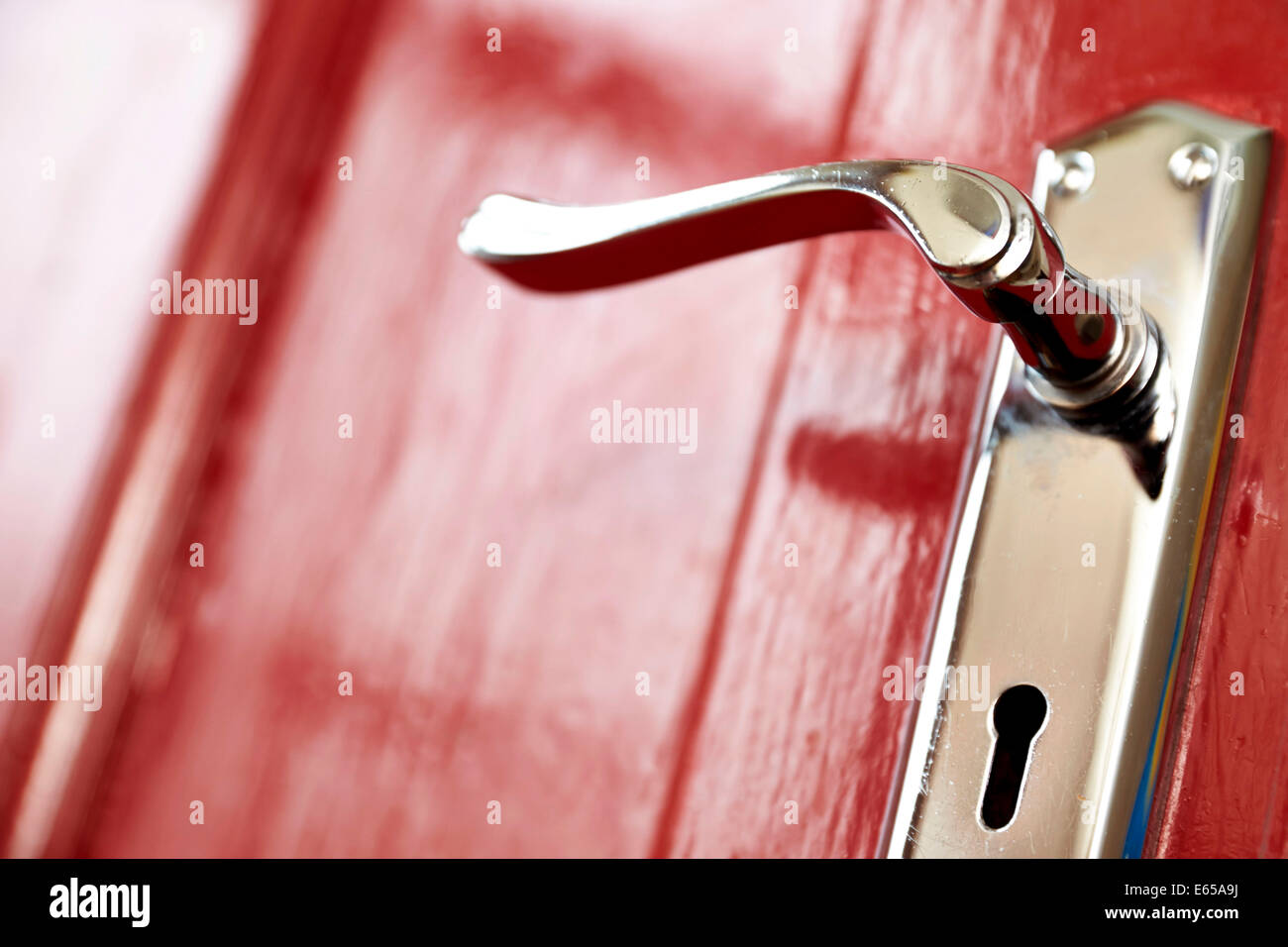 Un metallo la maniglia dello sportello e la serratura di una Rossa porta anteriore su una casa. Foto Stock