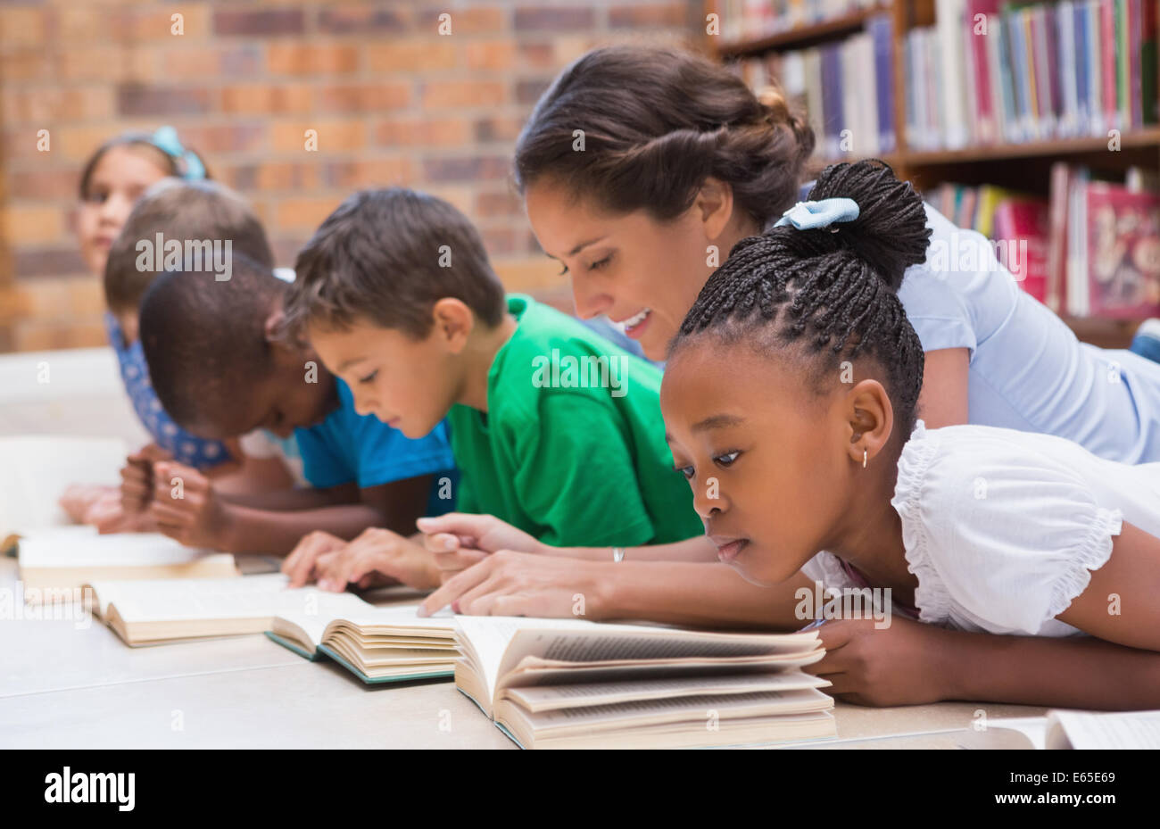 Carino gli alunni e gli insegnanti che giace sul piano nella libreria Foto Stock