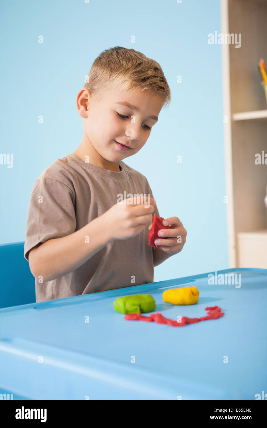 Carino piccolo ragazzo giocando con la creta per modellare in aula Foto Stock