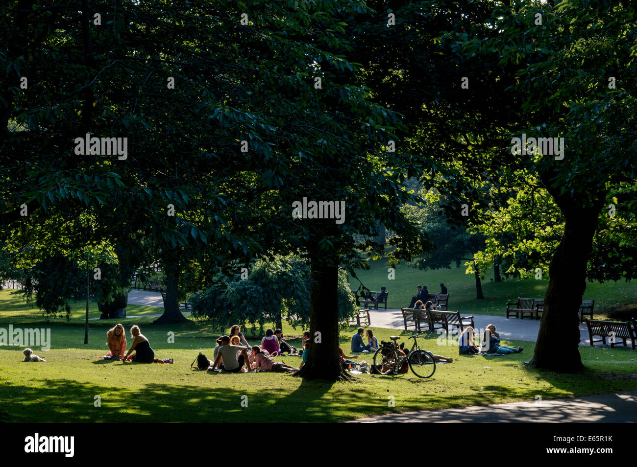 Turisti che si godono la serata estiva sun nei giardini di Princes Street, Edinburgh Foto Stock