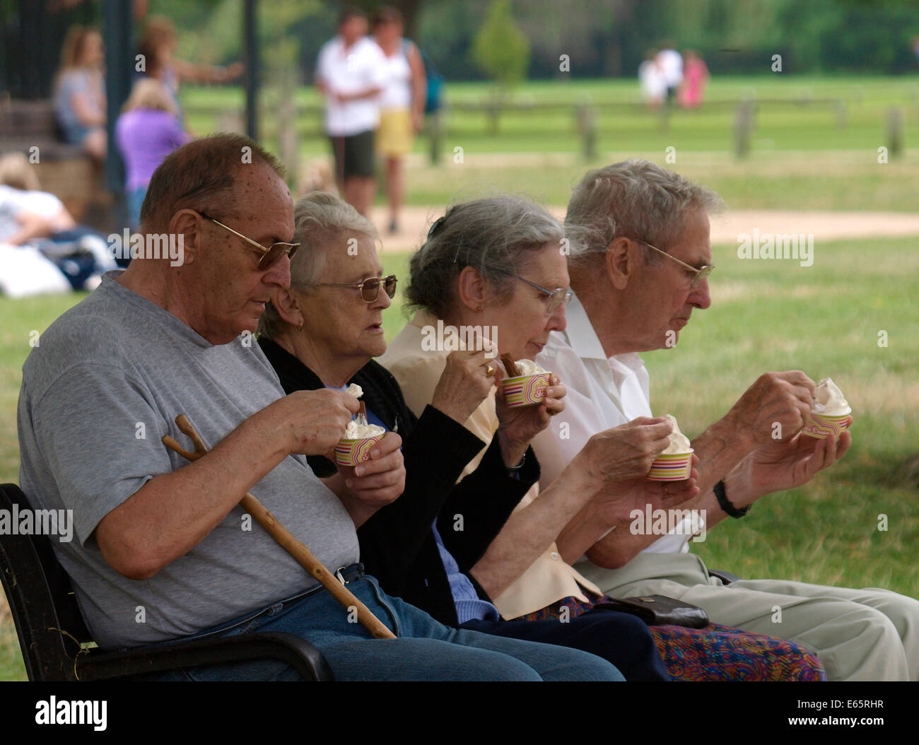 Quattro pensionati seduti su una panchina nel parco a mangiare il gelato, Stratford upon Avon, Regno Unito Foto Stock