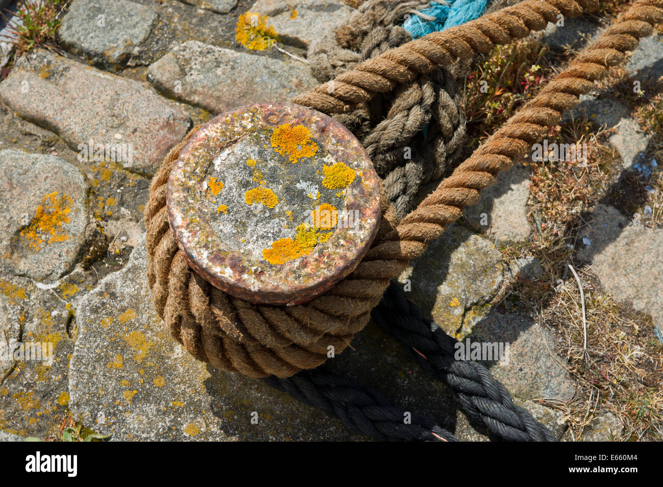 Un arrugginito post di ormeggio con corda di canapa da una nave avvolta ad anello intorno ad esso Foto Stock