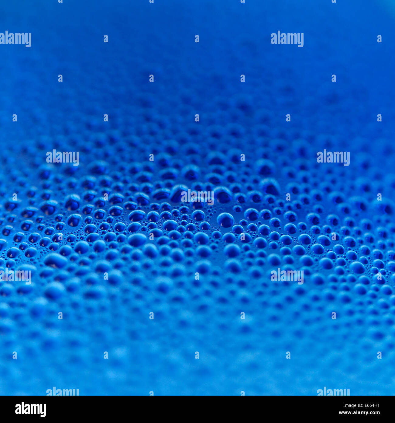 Gocce d'acqua in bottiglia blu sullo sfondo Foto Stock