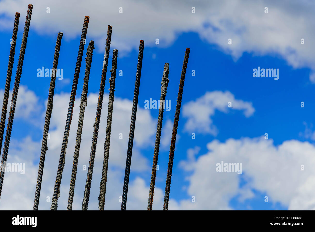 Costruzione rebar sporgente al di fuori del terreno contro un nuvoloso cielo blu Foto Stock