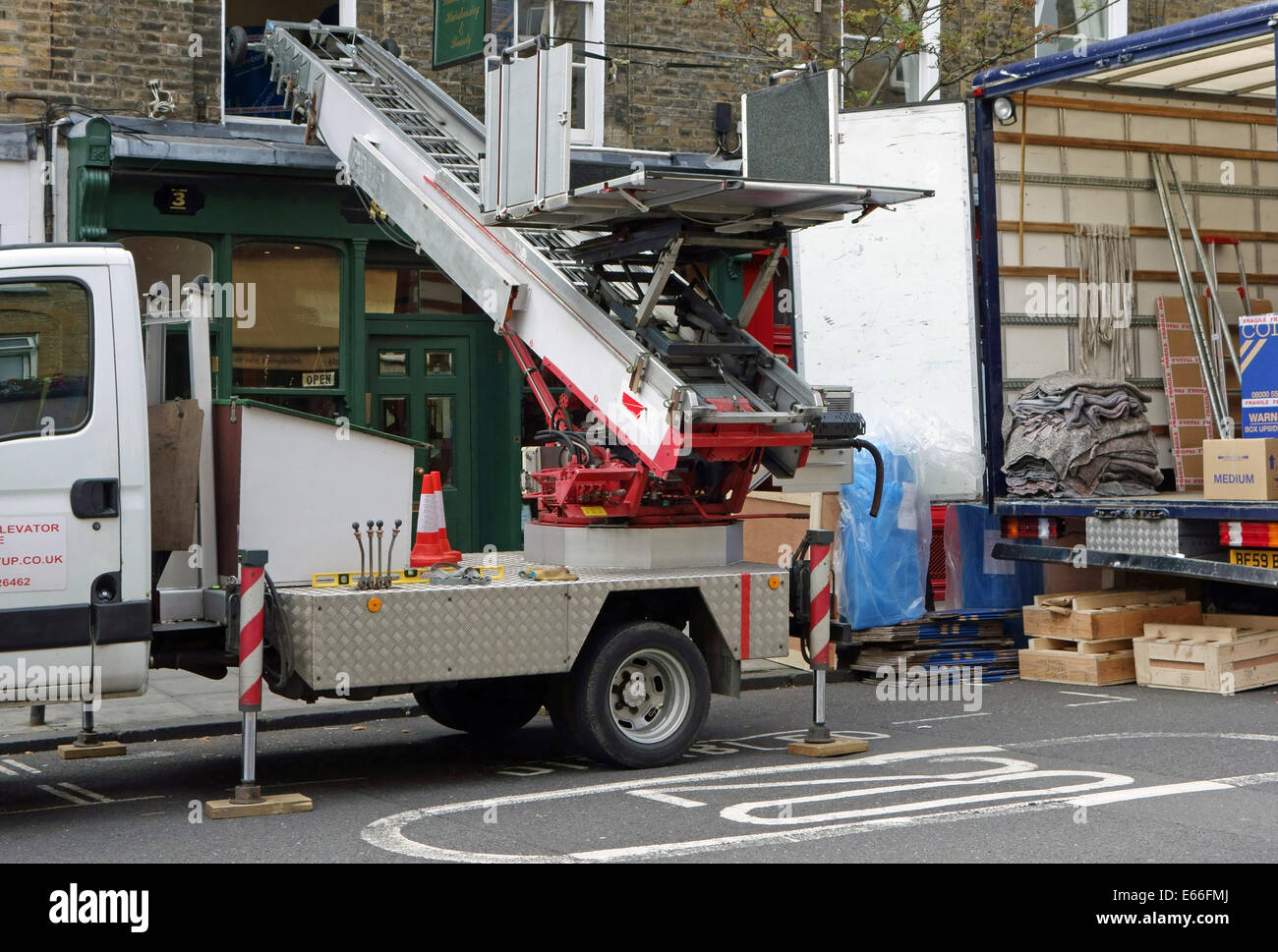 Traslochi uomini tramite ascensore per sollevare possedimenti al primo piano finestra, Londra Foto Stock