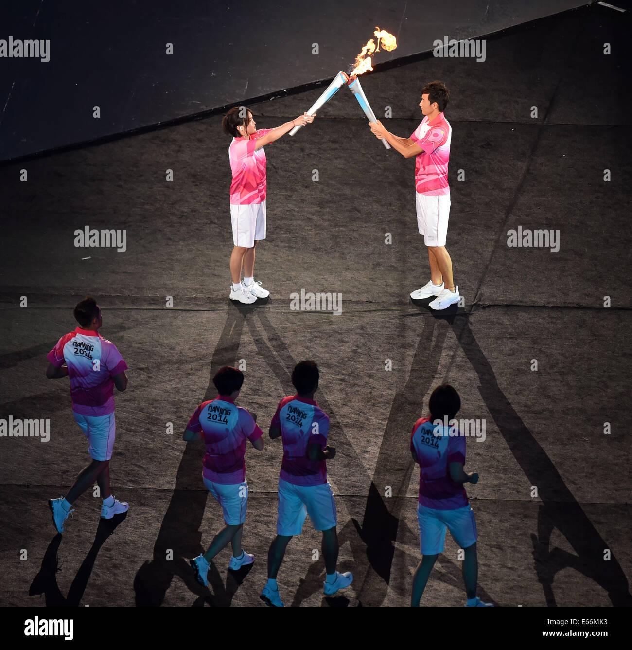 (140816) -- NANJING, Agosto 16, 2014 (Xinhua) -- Torchbearer gara cinese walker Chen Ding (R) passa la fiamma al subacqueo cinese Chen Ruolin durante la cerimonia di apertura di Nanjing 2014 Estate Olimpiadi della Gioventù in Nanjing, a est della capitale cinese della provincia di Jiangsu, Agosto 16, 2014.(Xinhua/Guo Yong) Foto Stock