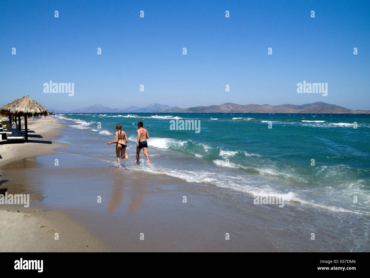 Le persone che eseguono lungo la spiaggia di Tingaki, Tingaki, isola di Kos, Grecia. Foto Stock