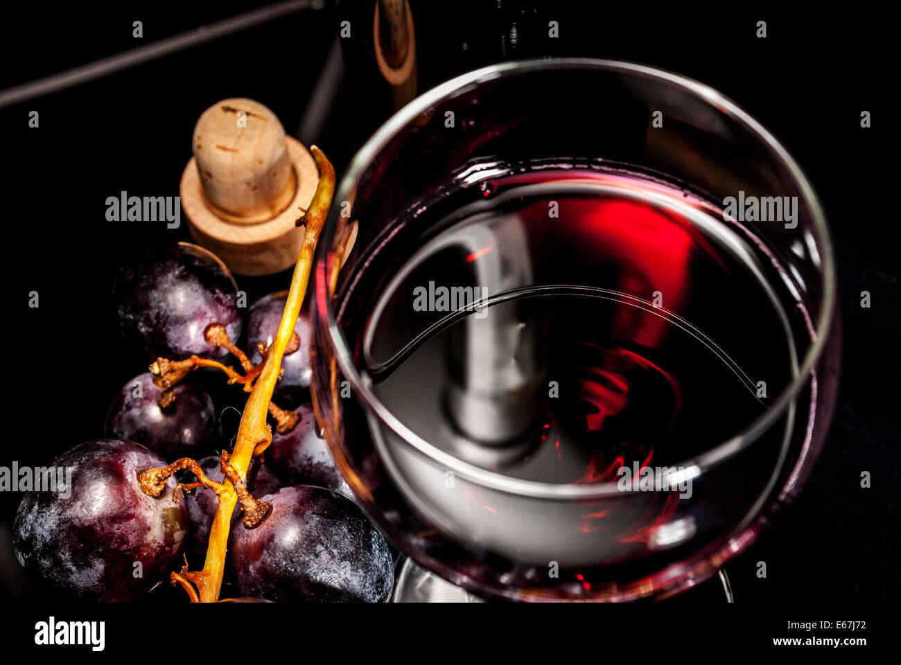Vino rosso con uva nera per riflettere sullo sfondo Foto Stock