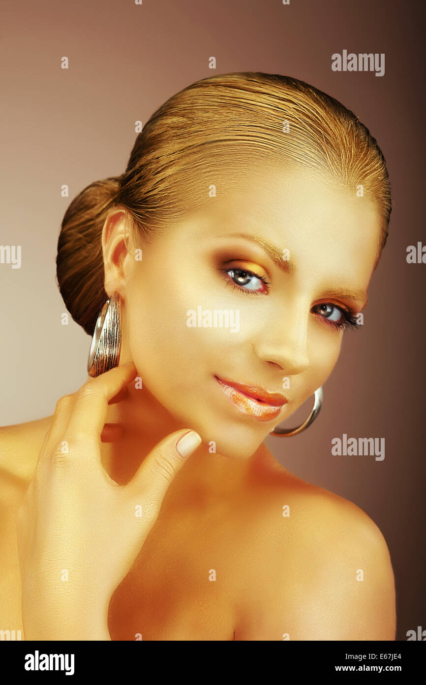 Affascinante signora con orecchini in argento e setosa pelle dorata Foto Stock