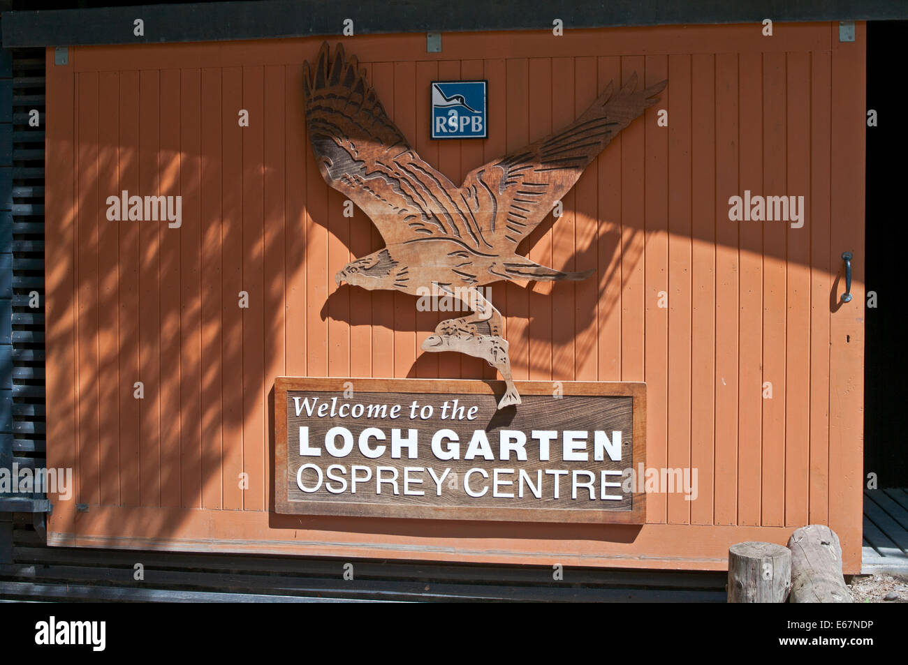 Segno di benvenuto sulla porta scorrevole di legno con intaglio del legno di osprey battenti con pesce, RSPB Loch Garten Osprey Centre, Cairngorms Foto Stock
