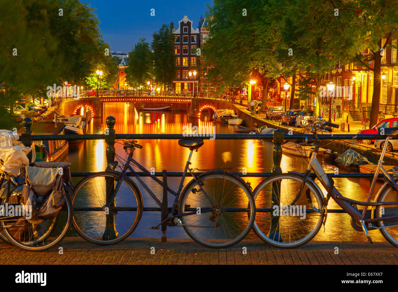 Illuminazione notturna di Amsterdam canal e il ponte con le tipiche case olandesi, imbarcazioni e biciclette, Holland, Paesi Bassi. Foto Stock