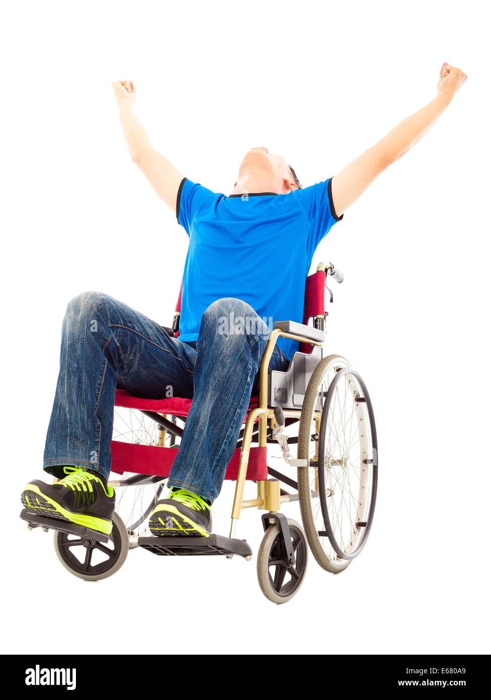 Eccitato giovane uomo seduto su una sedia a rotelle e alzando le mani Foto Stock