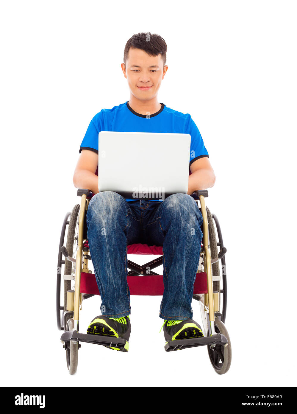 Felice giovane uomo seduto su una sedia a rotelle con un laptop Foto Stock