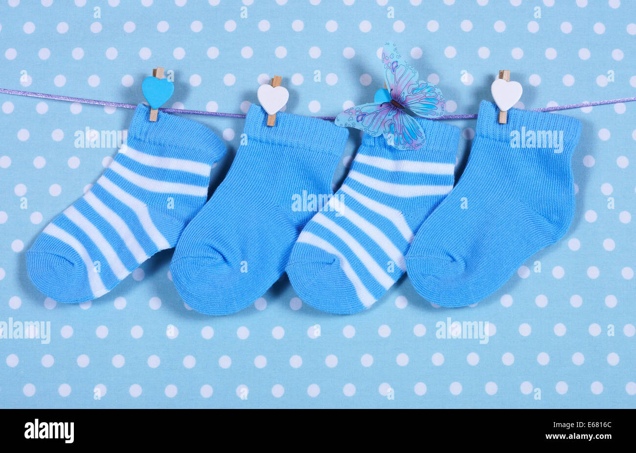 Baby boy vivaio calzini blu e butterfly appesi da pioli su una linea contro un blue polka dot sfondo Foto Stock