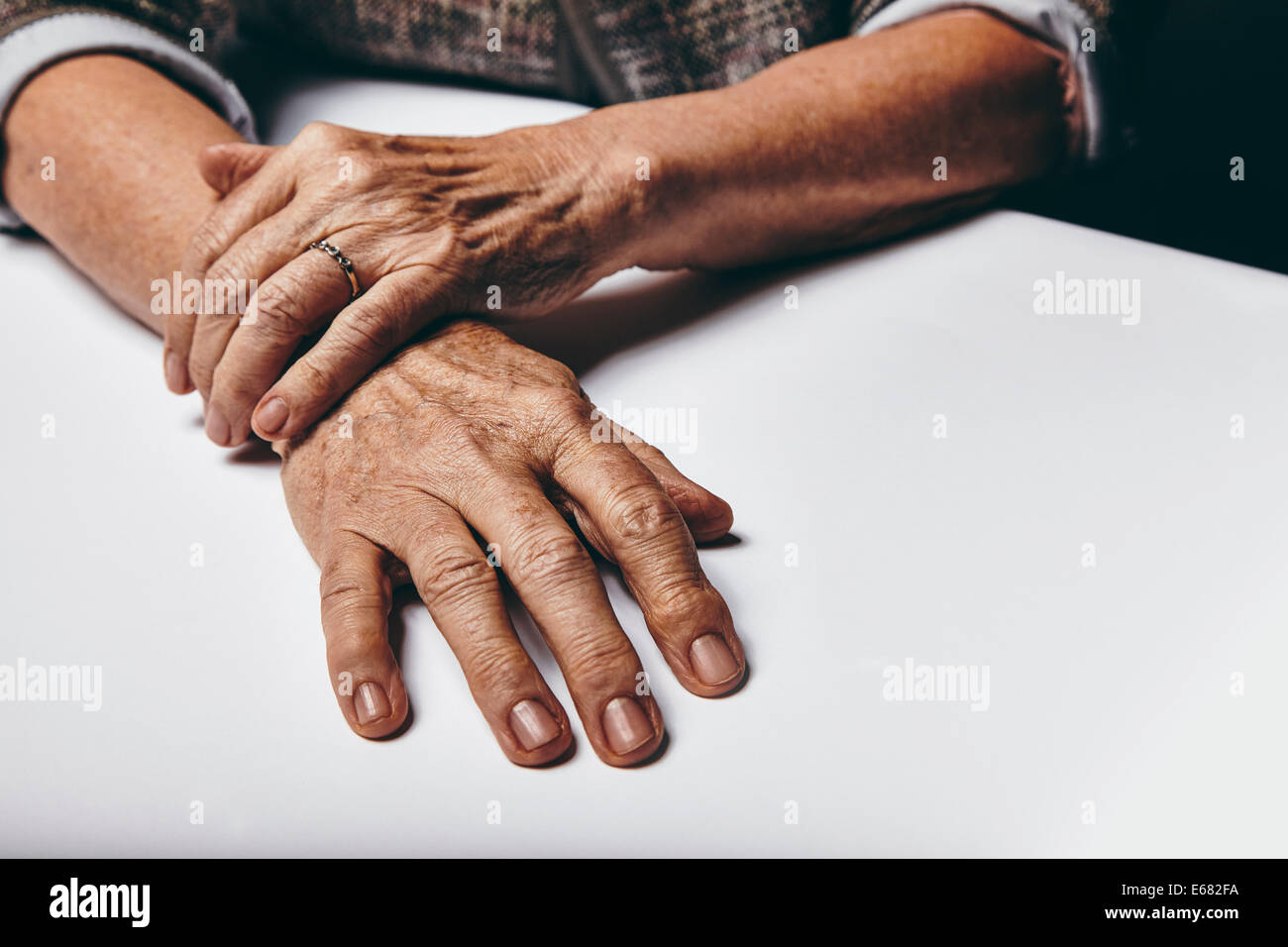 Close-up immagine della donna senior seduti a un tavolo con focus sulle mani. Vecchio mani femminili su una scrivania. Foto Stock