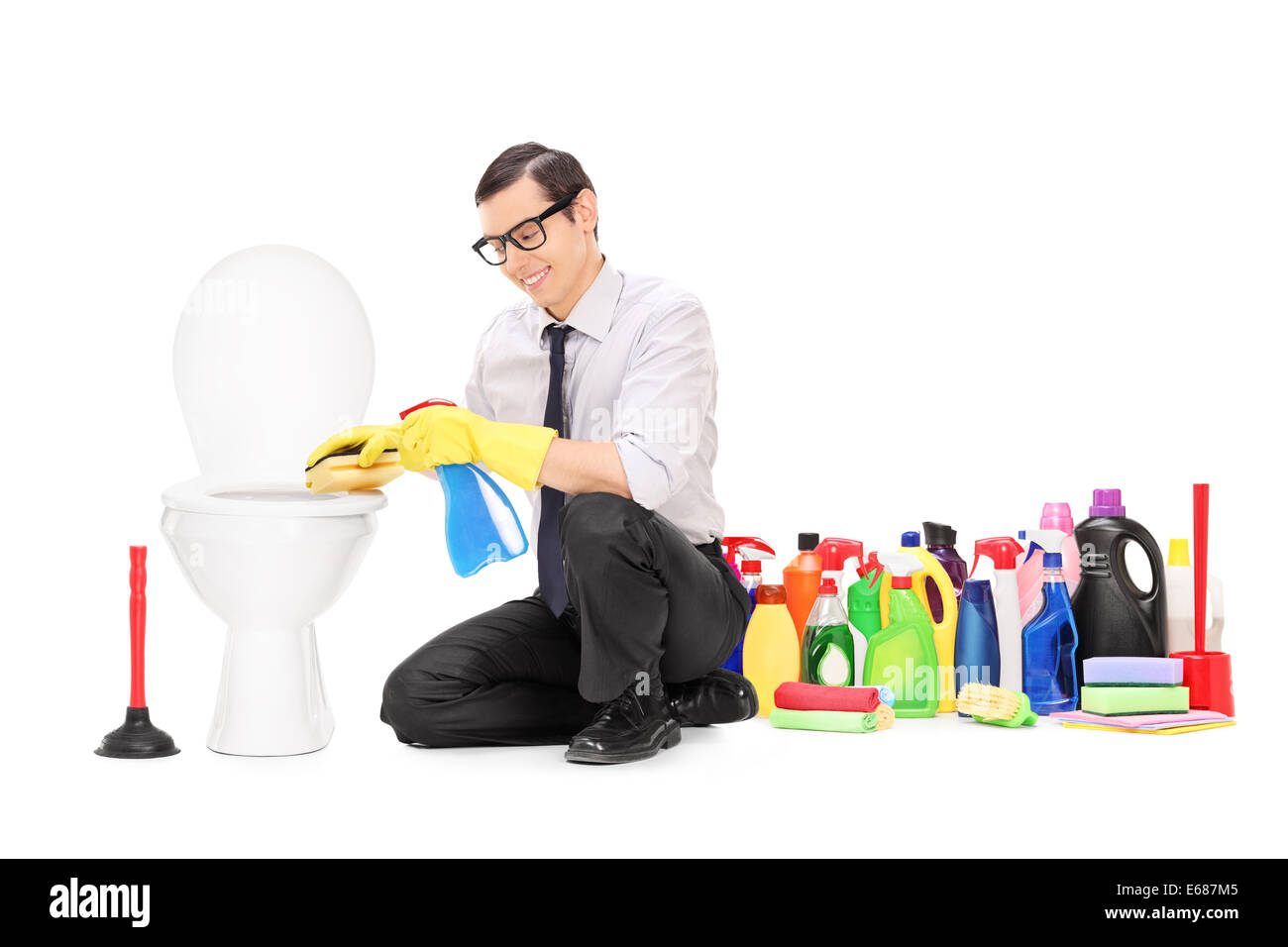 Uomo seduto da un wc con mazzetto di prodotti di pulizia dietro di lui Foto Stock