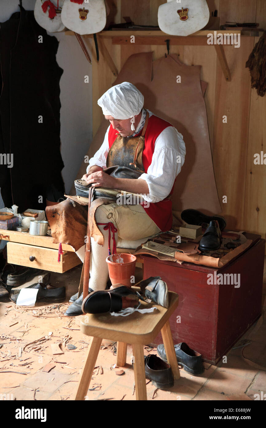 Calzolaio Riparazione di scarpe, utilizzando strumenti tradizionali e indossando indumenti periodo della guerra rivoluzionaria americana. Foto Stock