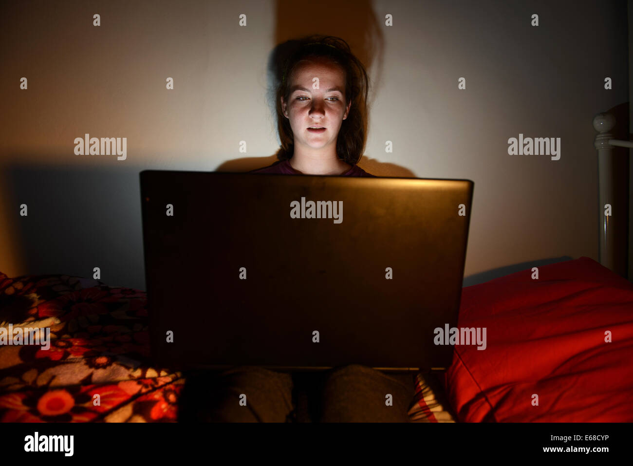 Computer portatile utilizzato da un bambino nella sua camera da letto, ragazza adolescente usando un computer portatile da sola nella sua camera da letto Foto Stock