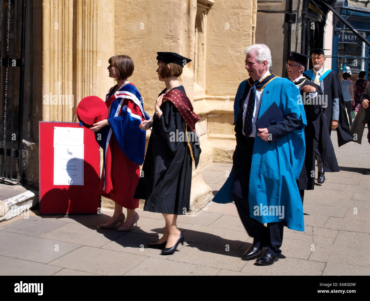 Persone che indossano abiti accademico entrando in San Giovanni Battista chiesa parrocchiale, Cirencester, Gloucestershire, Regno Unito Foto Stock