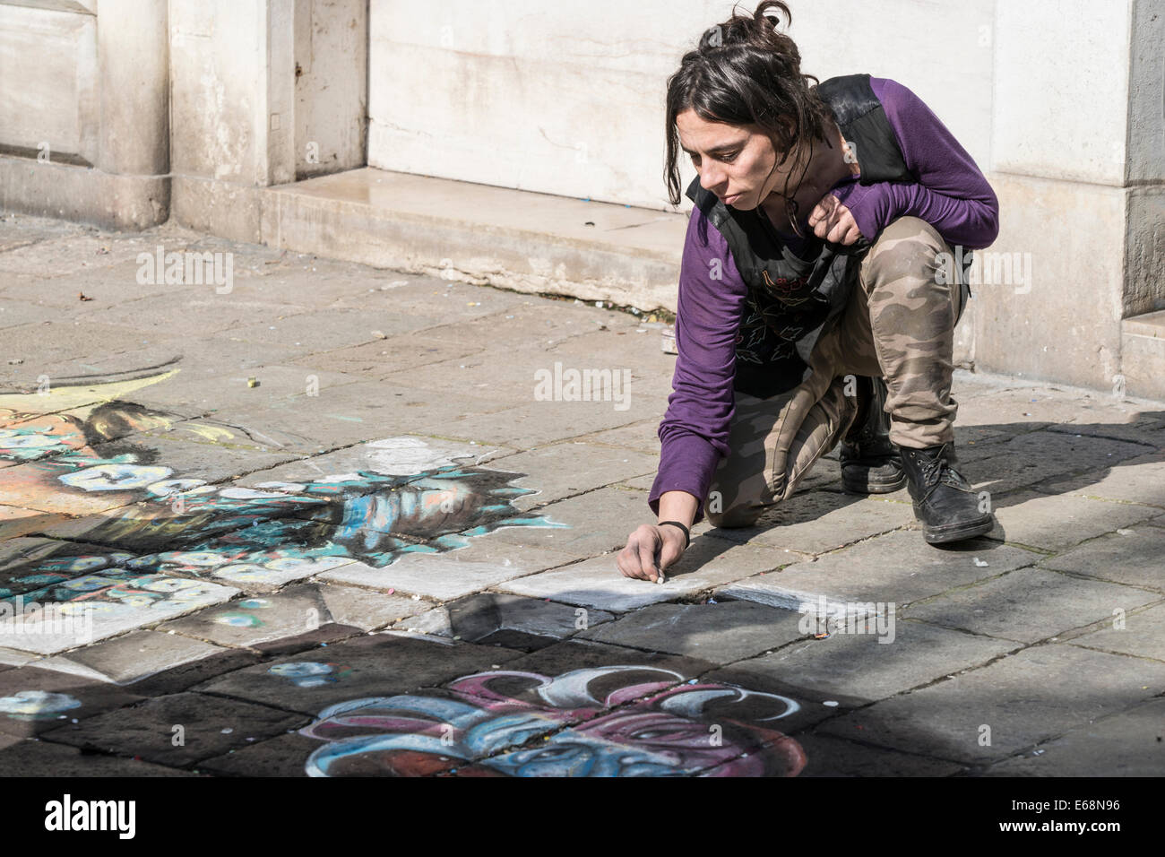 Una femmina di artista di strada non colorati disegni sul marciapiede durante il carnevale su una principale arteria pedonale a Venezia. Foto Stock