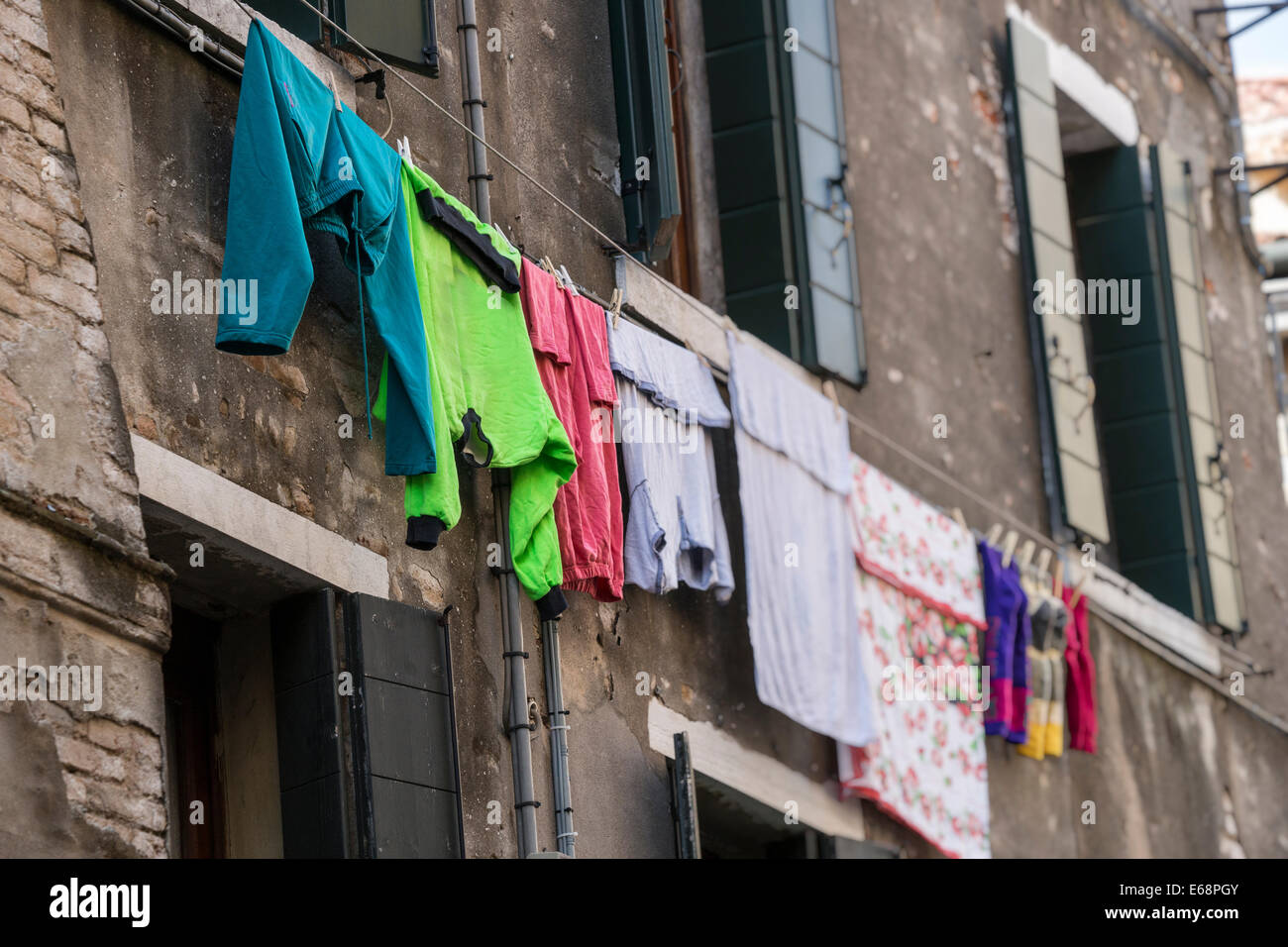 Abiti colorati appesi sulla linea fuori casa vecchia a Venezia. Foto Stock