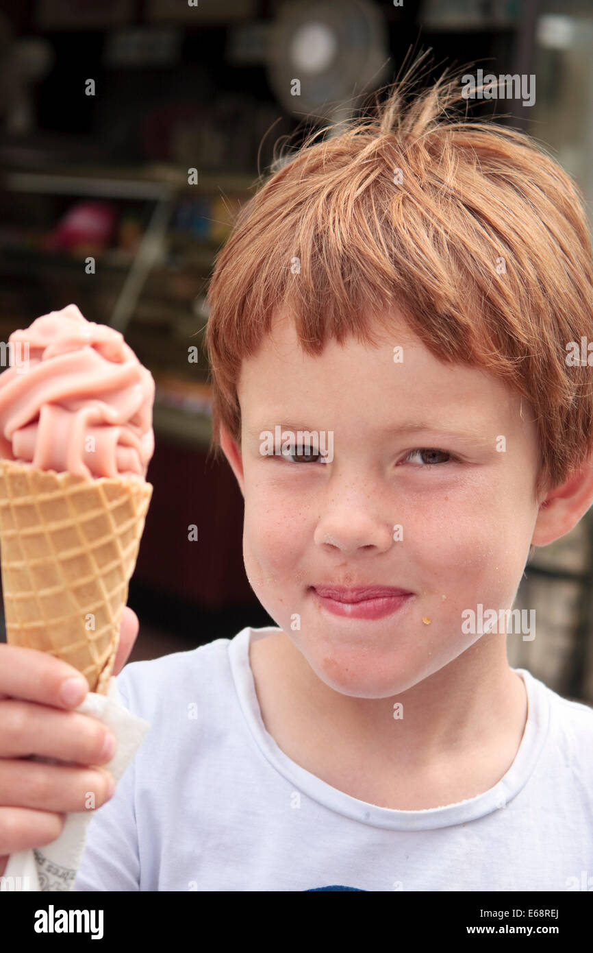 Cinque anni di vecchio ragazzo tenendo una fragola gelato in un cono Foto Stock