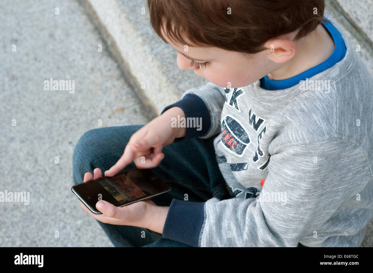 Bambino guardando le immagini sul telefono cellulare Foto Stock