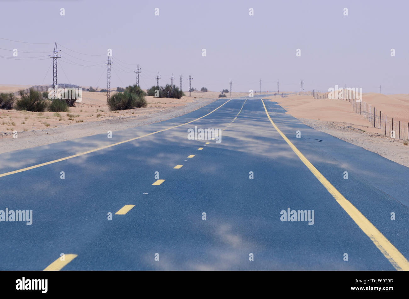 Soffiatura di sabbia di fronte all'autostrada strada attraverso il deserto di Dubai, Emirati Arabi Uniti EMIRATI ARABI UNITI. Foto Stock