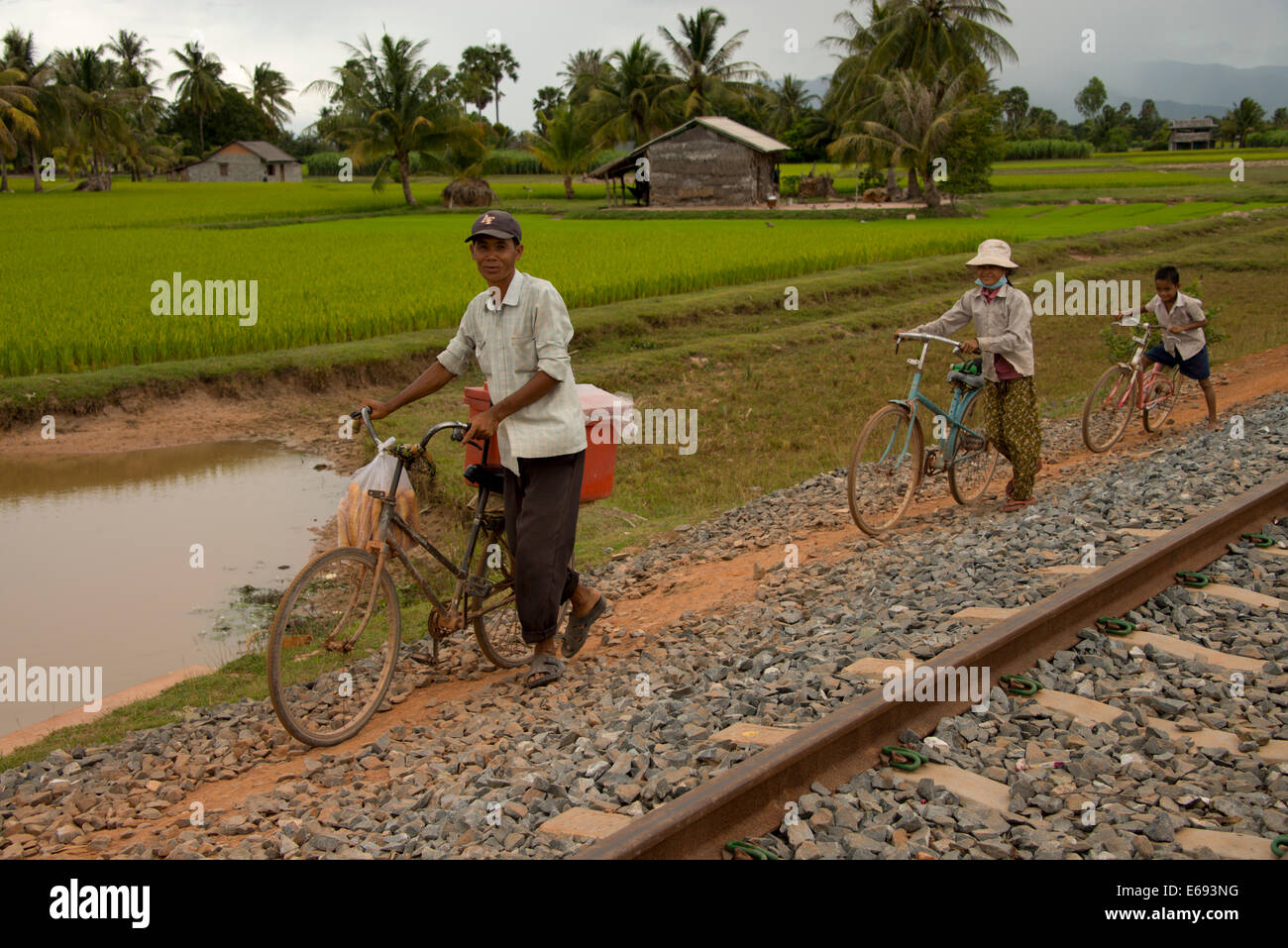 Uomo e donna e bambino ciclo lungo la linea ferroviaria, Cambogia Foto Stock