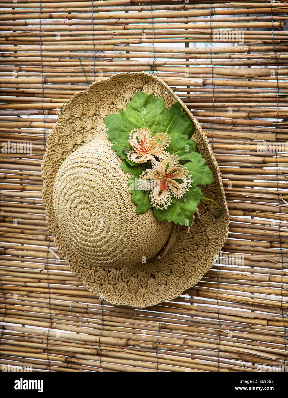 Signora cappello di paglia con fiore decorativo nastro appeso sulla parete  di bambù Foto stock - Alamy