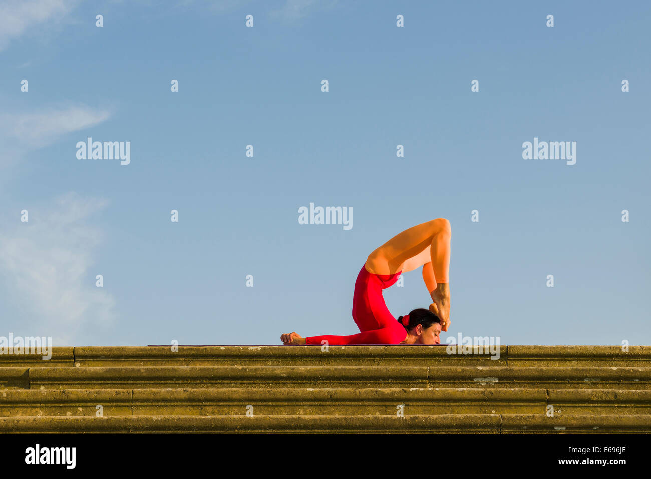 Giovane donna pratica di Hatha yoga, all'aperto, che mostra la posa poorna Shalabhasana, piena Locust Foto Stock