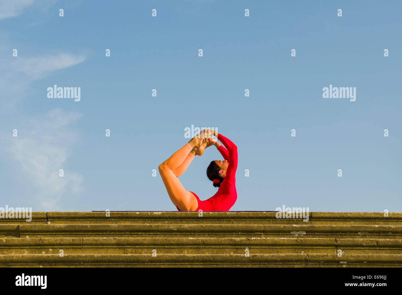 Giovane donna pratica di Hatha yoga, all'aperto, che mostra la posa Dhanurasana, posa di prua Foto Stock