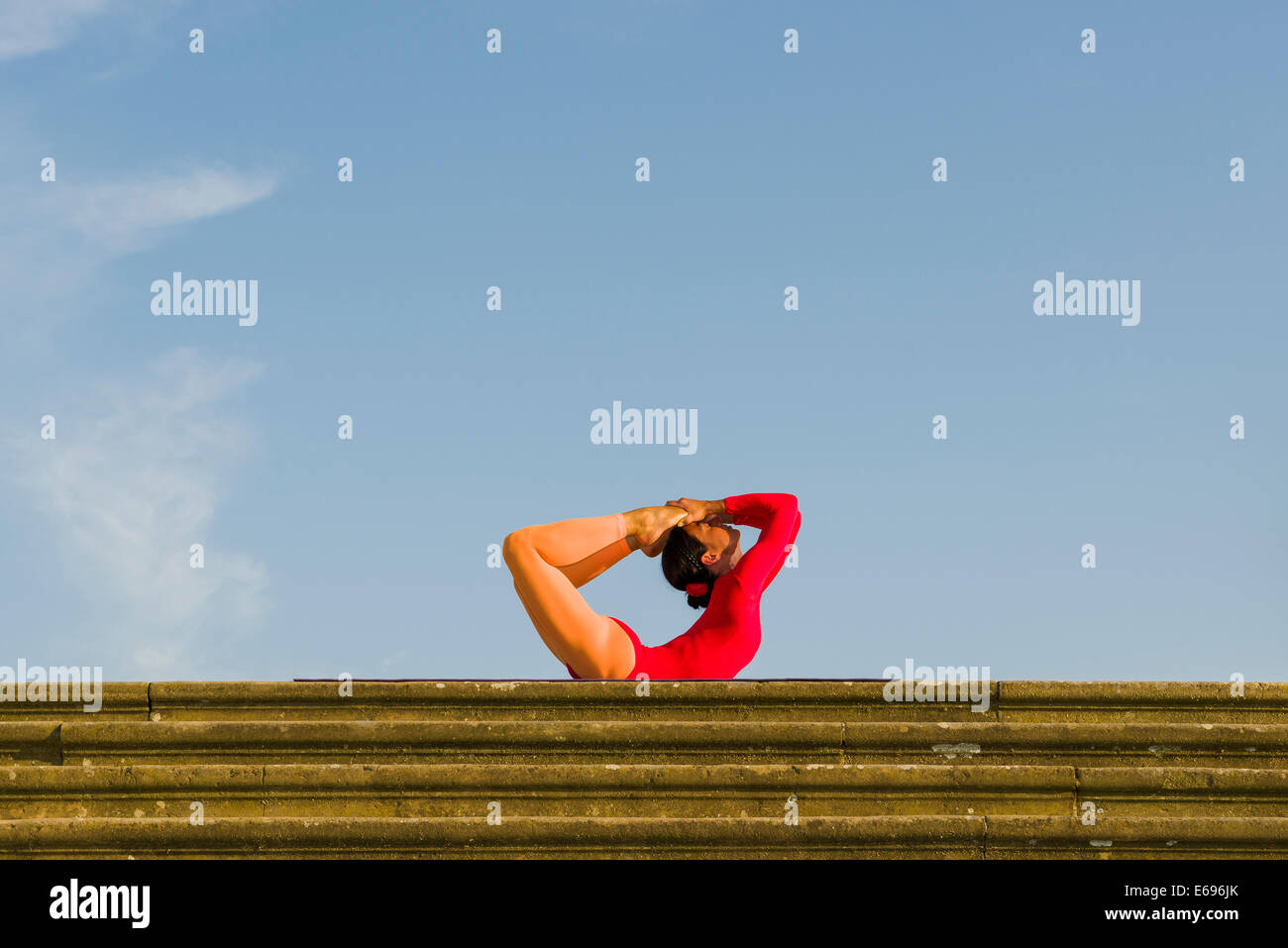 Giovane donna pratica di Hatha yoga, all'aperto, che mostra la posa Dhanurasana, posa di prua Foto Stock