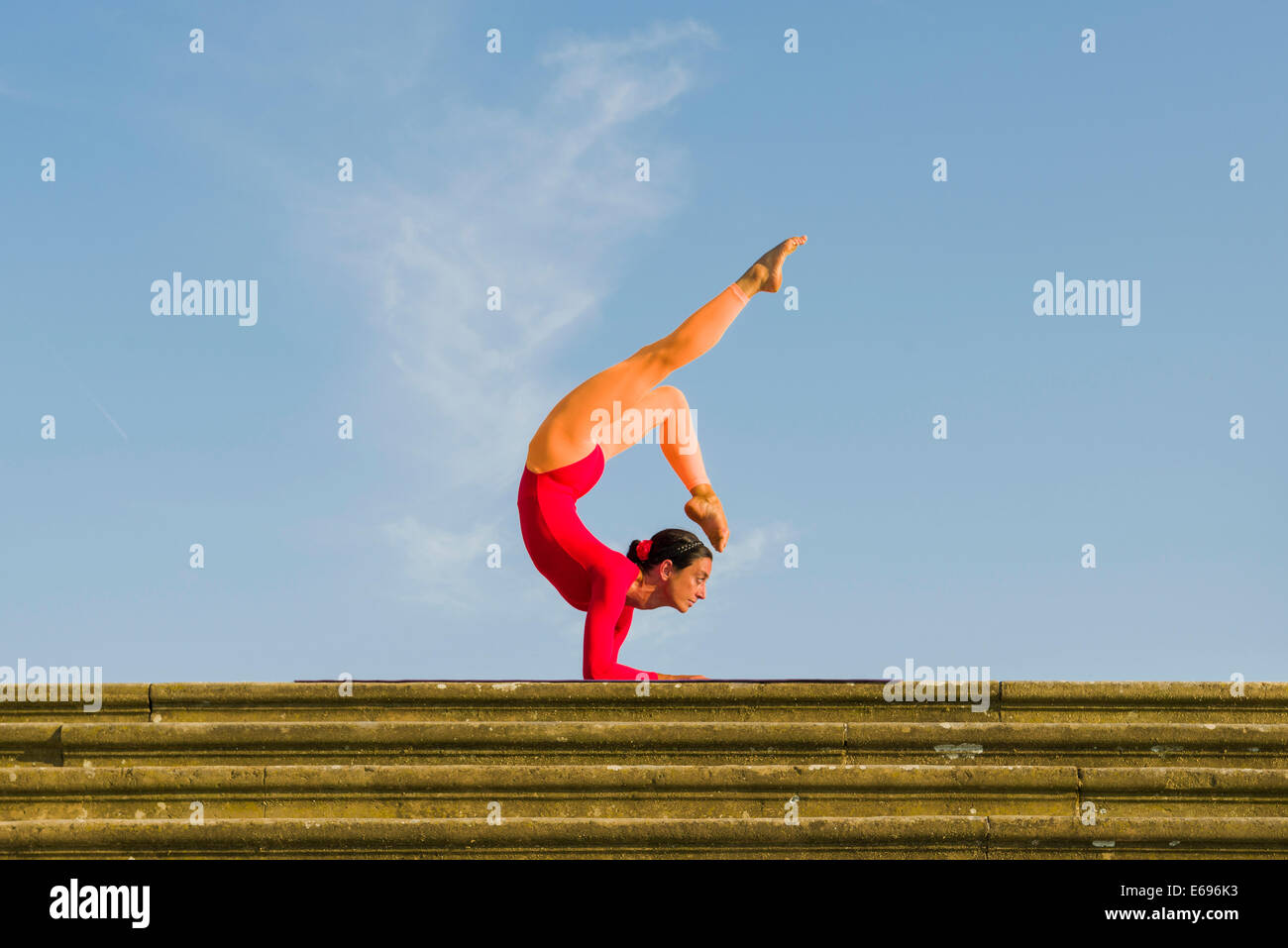 Giovane donna pratica di Hatha yoga, all'aperto, che mostra la posa Vrischikasana, Scorpion pongono Foto Stock