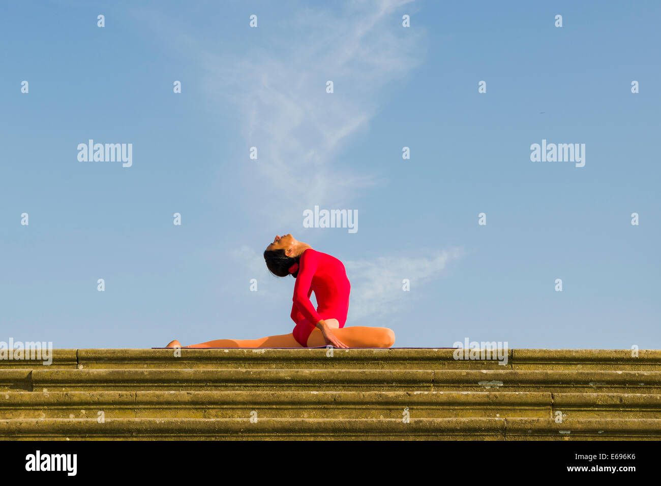 Giovane donna pratica di Hatha yoga, all'aperto, che mostra la posa Kapotasana, Piccione pongono Foto Stock