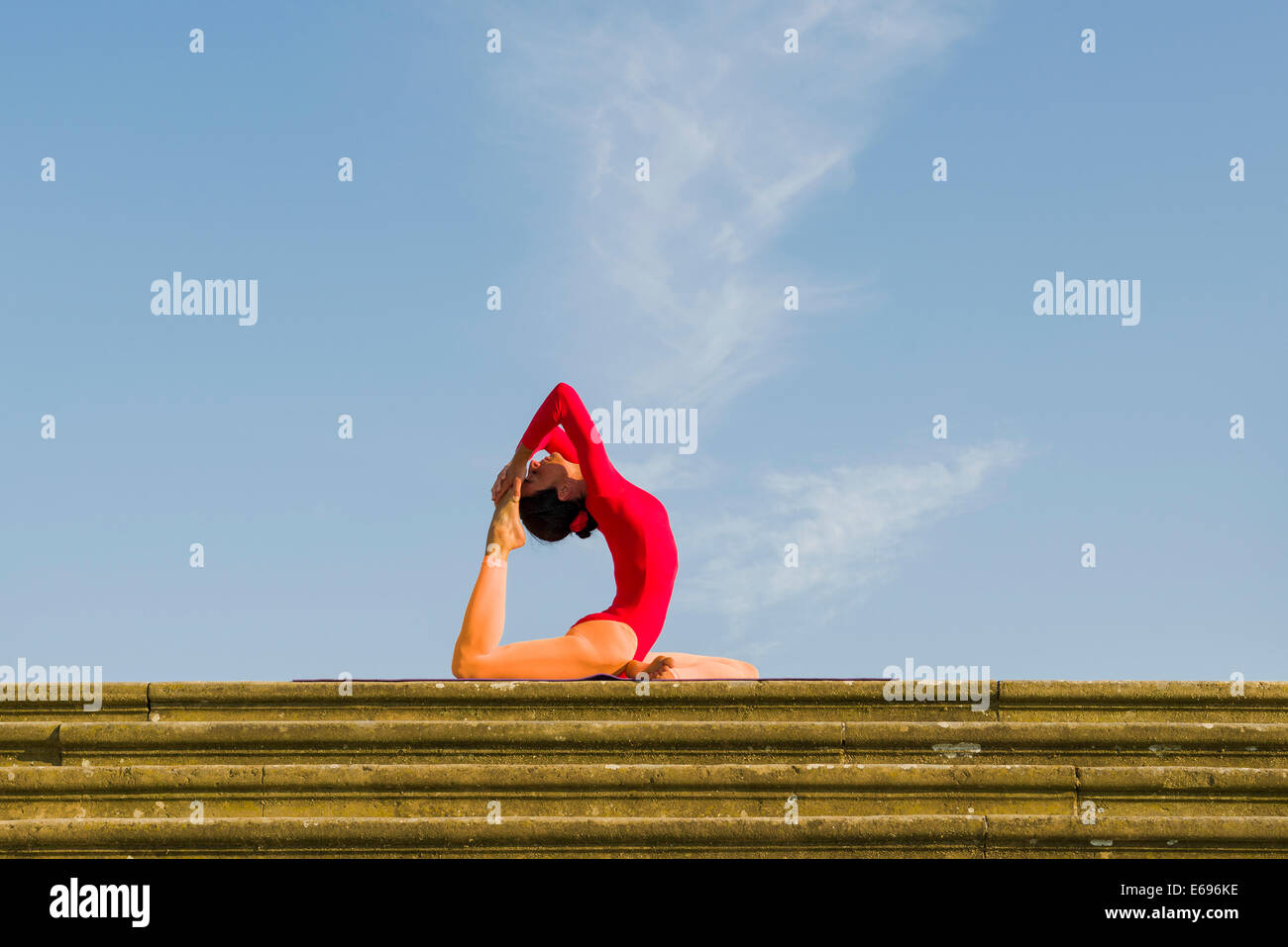 Giovane donna pratica di Hatha yoga, all'aperto, che mostra la posa Kapotasana, Piccione pongono Foto Stock